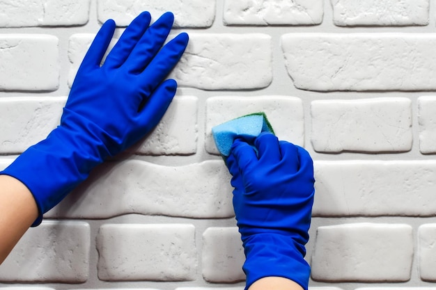 Worker's hands in rubber protective gloves with a rag wiping the surface of a table or wall in a room bathroom kitchen The concept of cleanliness