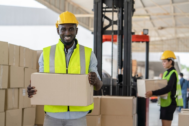 Worker in safety vest and helmet holding cardboard box