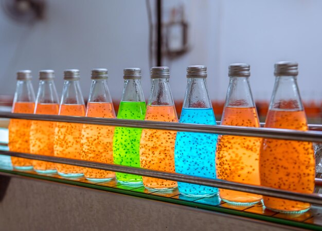 worker of science in bottle beverage factory wearing safety uniform face mask discussion and working to check quality of drink Basil seed produce on conveyer before distribution to marke