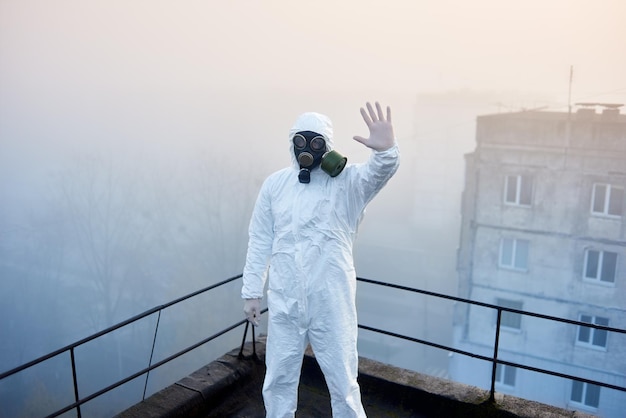 Worker scientist wearing protective coverall and gas mask doing ecological tests on the roof