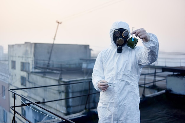 Worker scientist wearing protective coverall and gas mask doing ecological tests on the roof