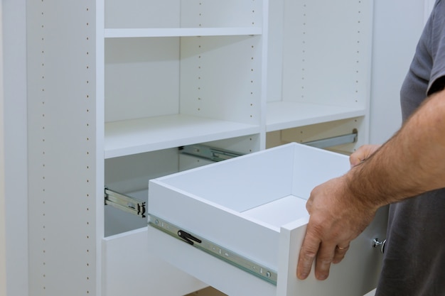 Photo worker sets the box installation the drawer for closet cabinet