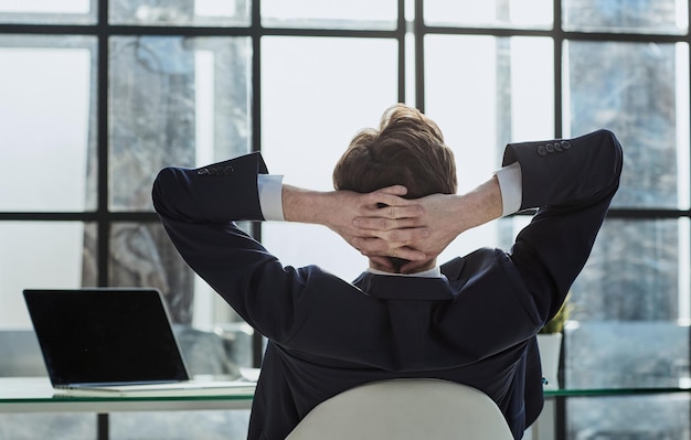 Worker sitting in office with hands behind his head