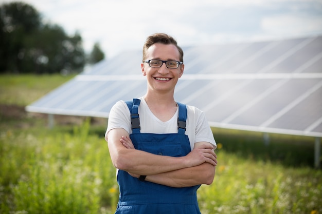 Worker standing in the field with solar with solar panels on backstage.