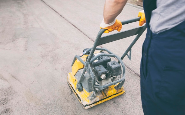 The worker tamping a gravel by the vibration plate