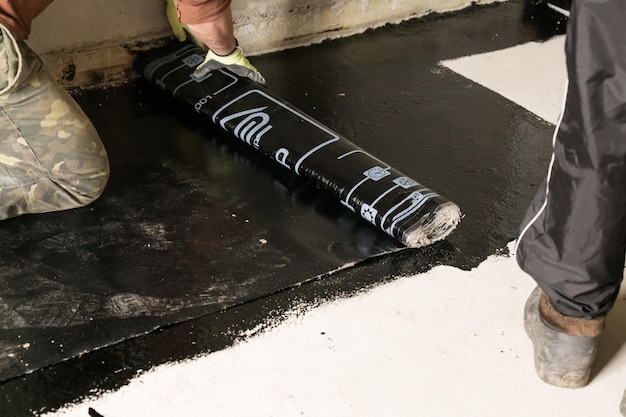 The worker untwists the roll of waterproofing and fastens it to the resin