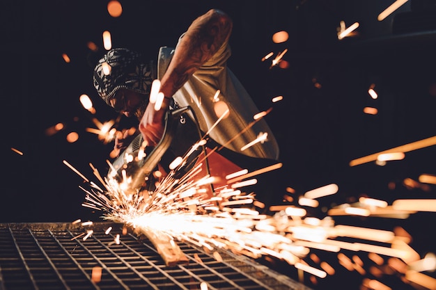 Worker Using Angle Grinder in Factory and throwing sparks