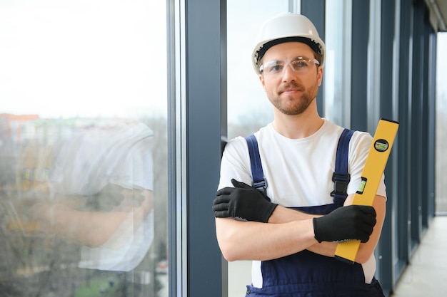 Worker using bubble level after plastic window installation indoors