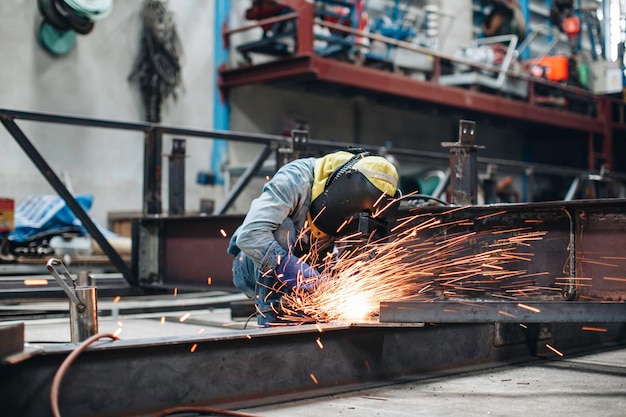 Worker using electric wheel spark grinding on metal steel is part of beam structure