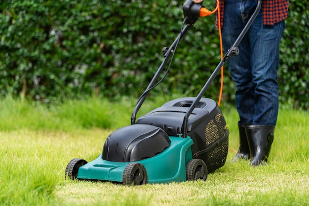 Worker using a lawn mower cutting grass at home