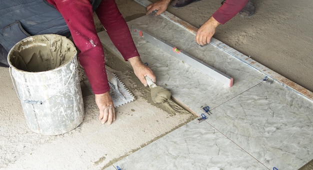 Worker using spatula and putting glue on floor