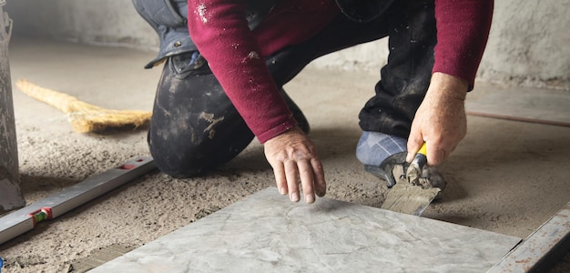 Worker using spatula and putting glue on floor