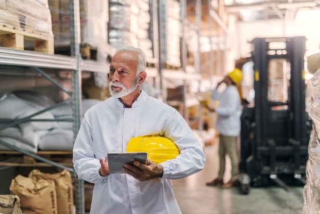 Worker using tablet and checking on goods in warehouse.