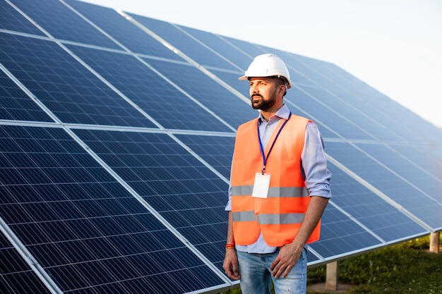 Worker in a vest and helmet stands on a solar station