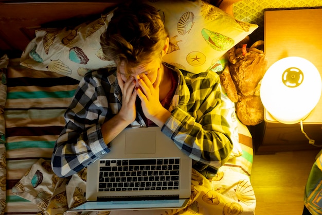 Worker wants to sleep while working with laptop in bed b