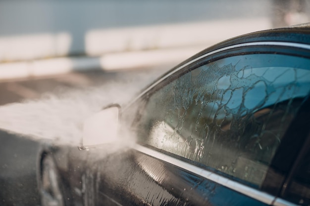 Worker washing car at selfservice car wash