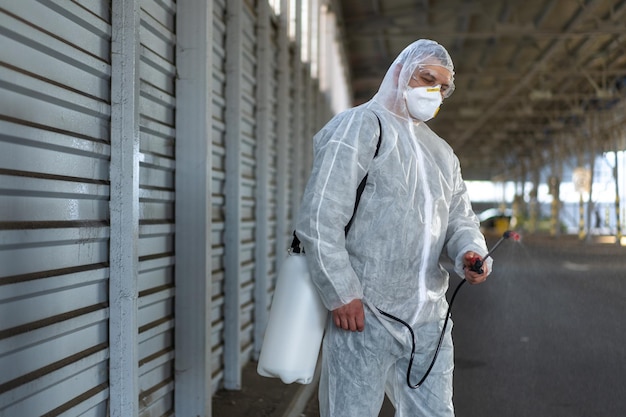 Worker wearing protective suit disinfection gear disinfect surface public place