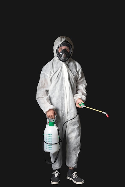 Worker wearing protective suit using disinfectant manual sprayer isolated on a grey background Male wearing protective clothing sterile uniform with facial mask hand pressure pump disinfecting