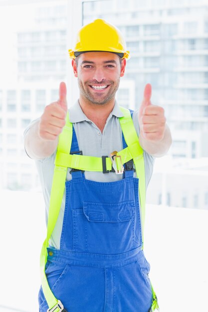 Worker wearing safety harness while gesturing thumbs up