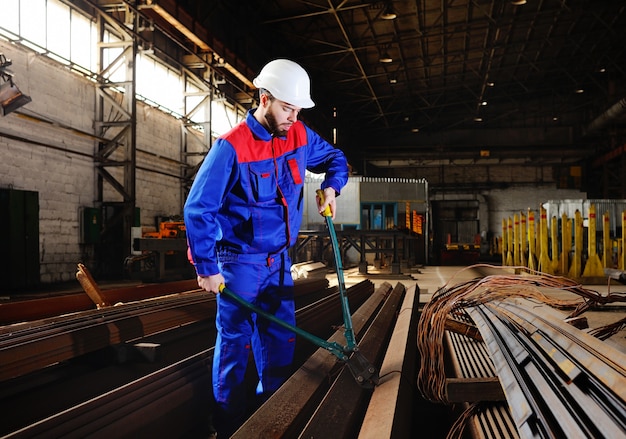 Worker in a white helmet bites the steel wire with wire cutters