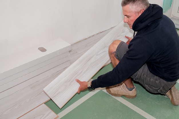 A worker who connects the laminate flooring during the renovation of the house.