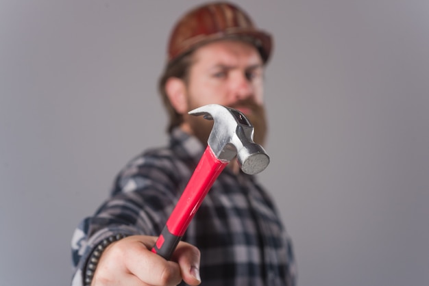 Worker with hammer. Bearded man with hammer in hands. Bearded worker. Portrait of man with hammer. Worker.