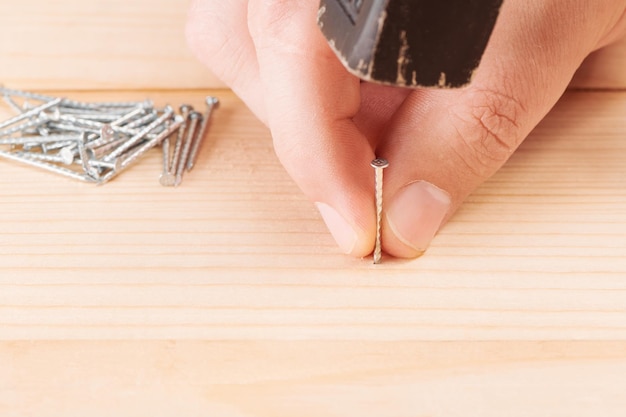 Worker with hammer and nail Hammering a nail into wooden board Carpenter working with hammer DIY Assembling Cloe up view with shallow DOF