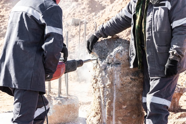 A worker with a jackhammer breaks concrete piles Felling the pile head with a hand tool Preparation of piles for mounting the foundation