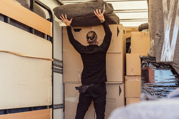 Worker with ponytail placing a bundle on top of cardboard boxes inside a moving truck