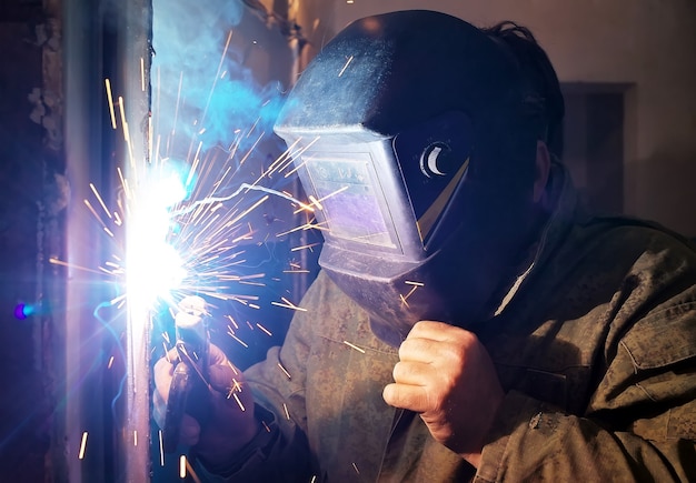 Photo worker with protective mask welding metal and sparks