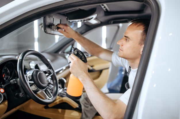 Worker with spray moisturizes car interior, dry cleaning and detailing