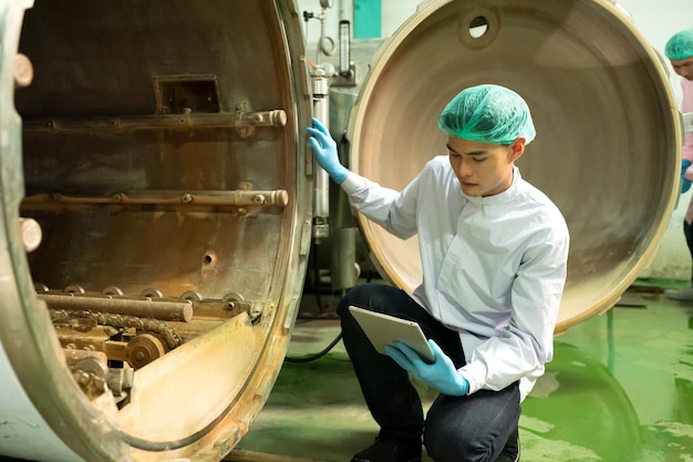 Worker working in drink factory at conveyor belt with fruit juice glass bottled in production line