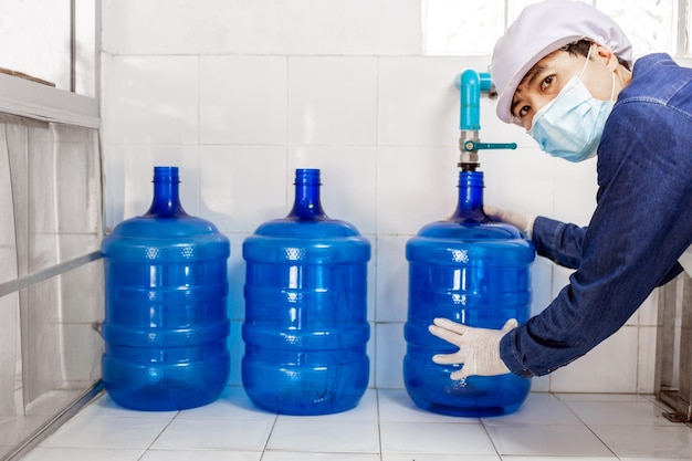 worker in workwear and with a protective mask on his face working producing drinking water