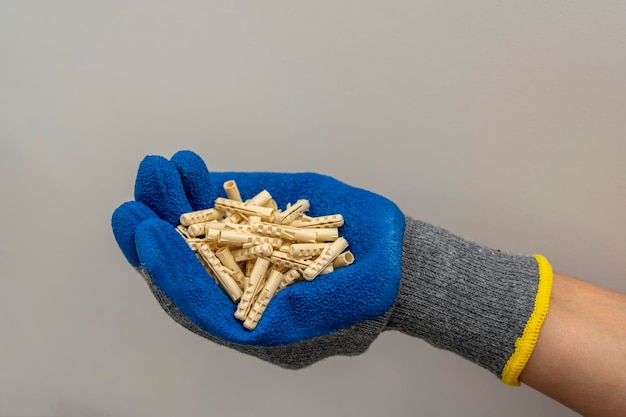 A worker39s hand in a protective glove holds a bunch of plastic dowel pins