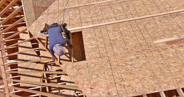 Workers applying nailing plywood panels a roof on the new house