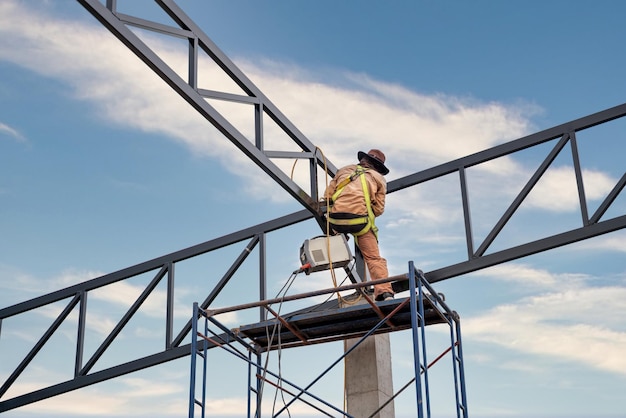 A workers are using Inverter welding machine Equipment for welding both ferrous and nonferrous metals MMA welding on the steel roof structure xA