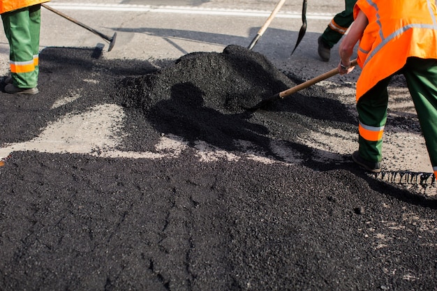 Workers on Asphalting paver machine during Road street repairing works