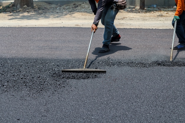 Workers on Asphalting paver machine during Road street repairing works.