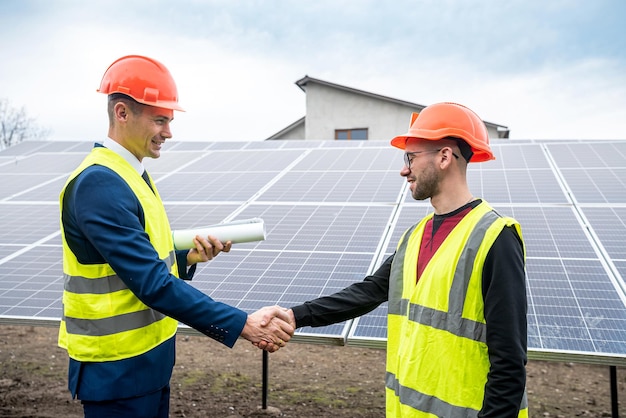 Workers in helmets two men shake hands after working on the installation of panels