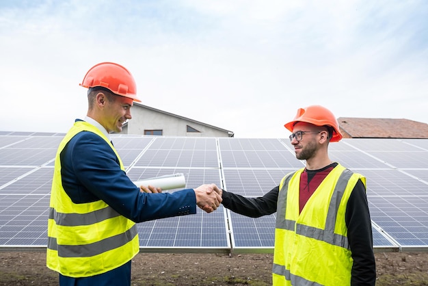 Workers on installation of solar economical panels shake hands after work