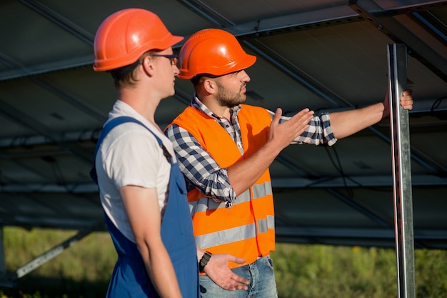 Workers installing photovoltaic panels at solar energy station.