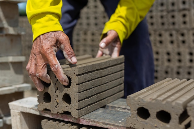 Workers lift hard clay bricks used in construction