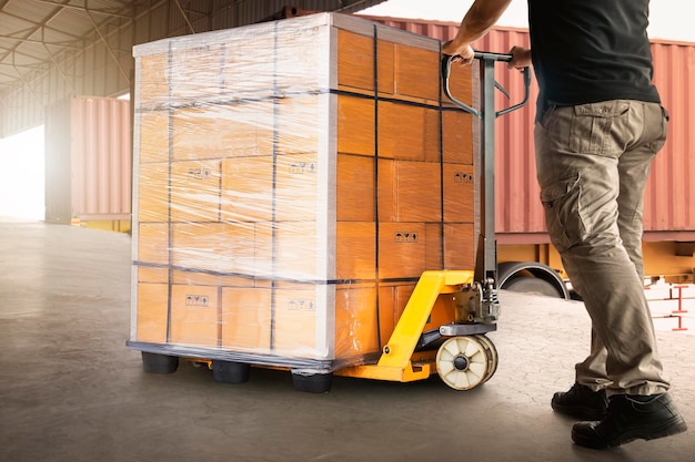 Photo workers unloading heavy pallet boxes into container truck supply chain shipment warehouse shipping