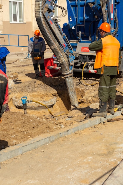 Workers use a suction excavator based on a MAN truck to sample soil in a well for communications