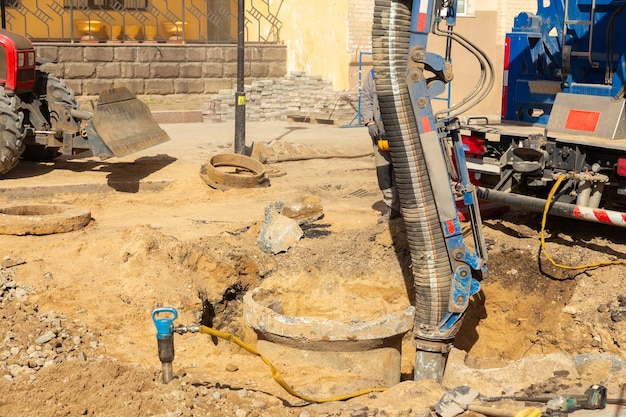 Workers use a suction excavator based on a truck to sample soil in a well for communications