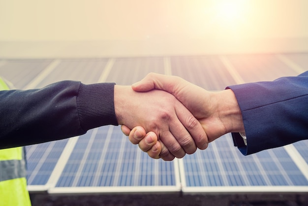 Workers in work clothes greet each other by the hand before starting work on solar panels