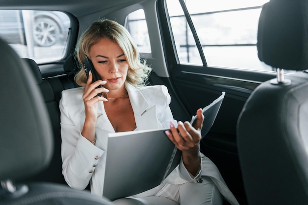 Working in the car Woman in formal clothes is indoors in the autosalon