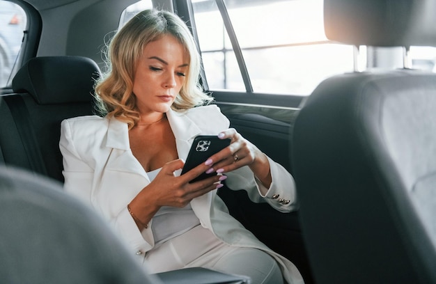 Working in the car Woman in formal clothes is indoors in the autosalon