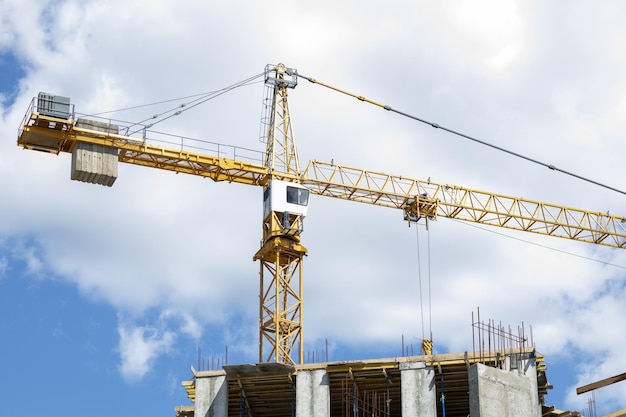 A working construction tower crane against a cloudy sky on a sunny day The concept of urban