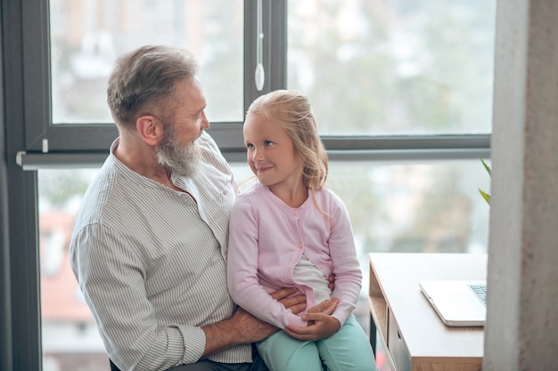 Working father. A businessman sitting at the table and holding his small daughter